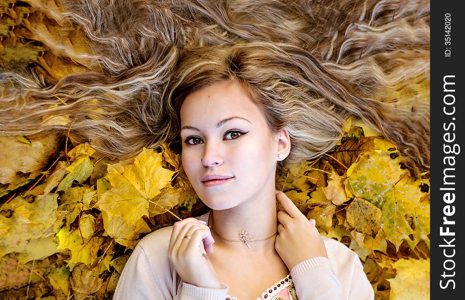 Beautiful woman lying with autumn leaves