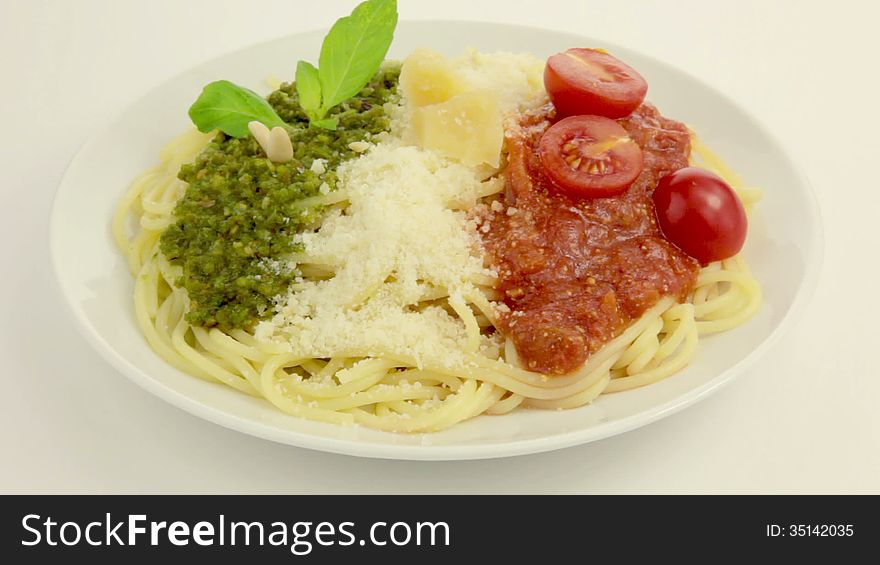 On a white plate rotates pasta. On top of pasta - Pesto, Parmesan and Tomato sauce - in the national colors of the Italian flag. On a white plate rotates pasta. On top of pasta - Pesto, Parmesan and Tomato sauce - in the national colors of the Italian flag