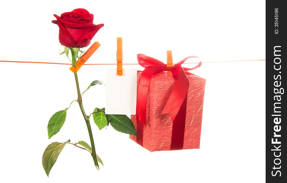 The rose, card and gift hang on a linen rope isolated on the white