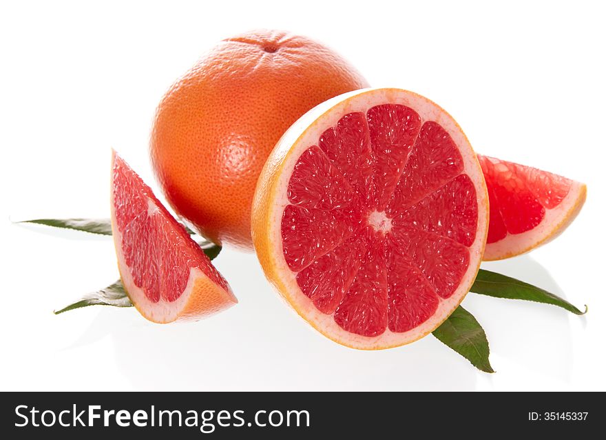 The cut grapefruit with leaves on a white background