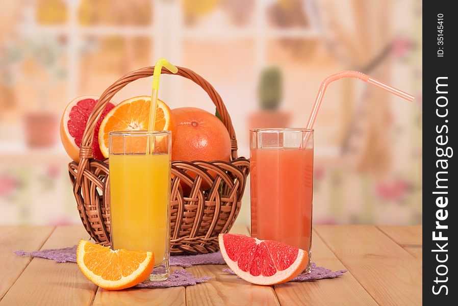 Orange and grapefruit juice in glasses on kitchen background