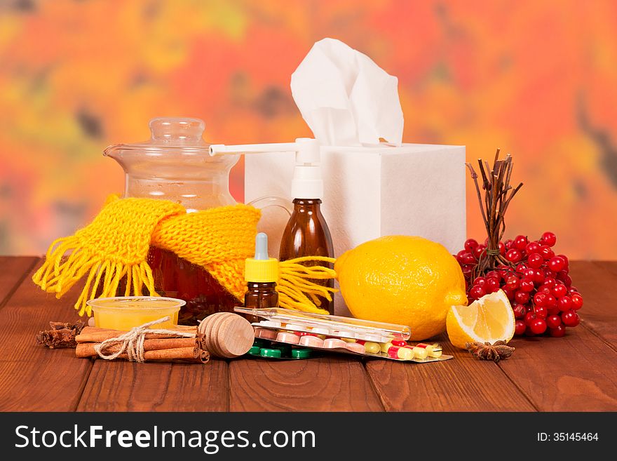 Various cold medicines on a table against autumn foliage