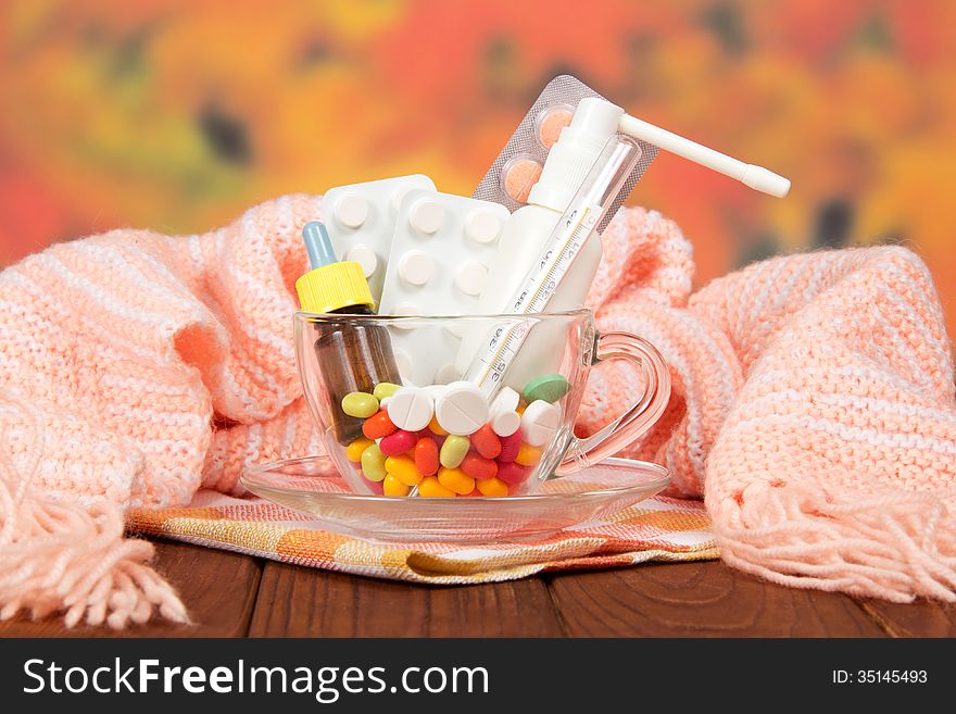 Different medicines in a cup against a scarf