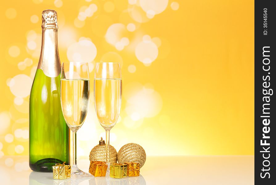 Bottle of champagne and two glasses on an abstract yellow background