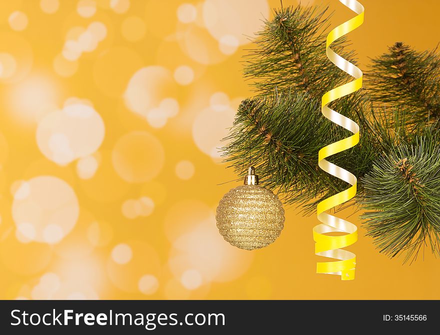 Branch of a New Year tree on an abstract yellow background. Branch of a New Year tree on an abstract yellow background