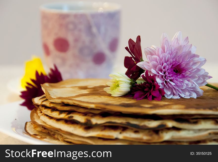 Flowers on pancakes with a cup of tea in the background