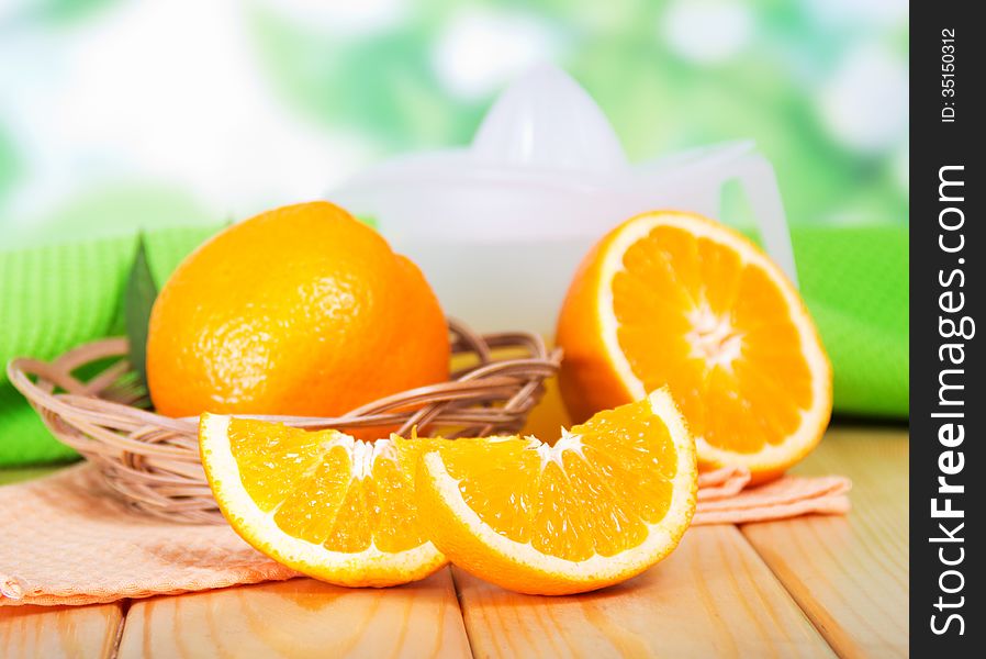 Segments of orange and a juice extractor against green foliage