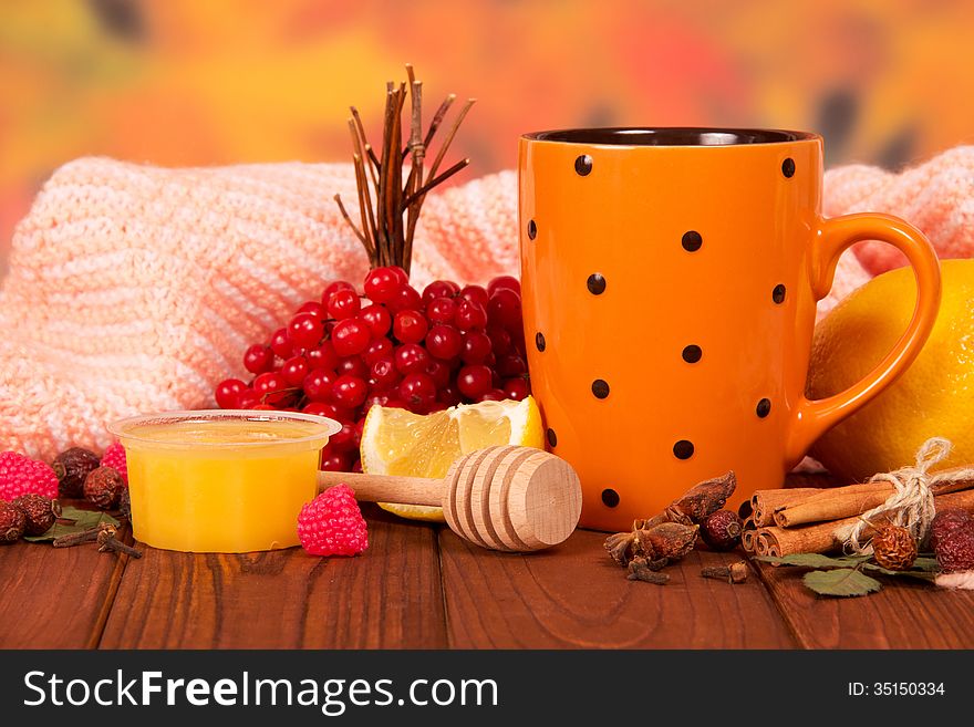 Honey, guelder-rose, lemon and cup of tea on wooden table