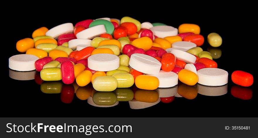 Handful of multi-colored tablets isolated on the black