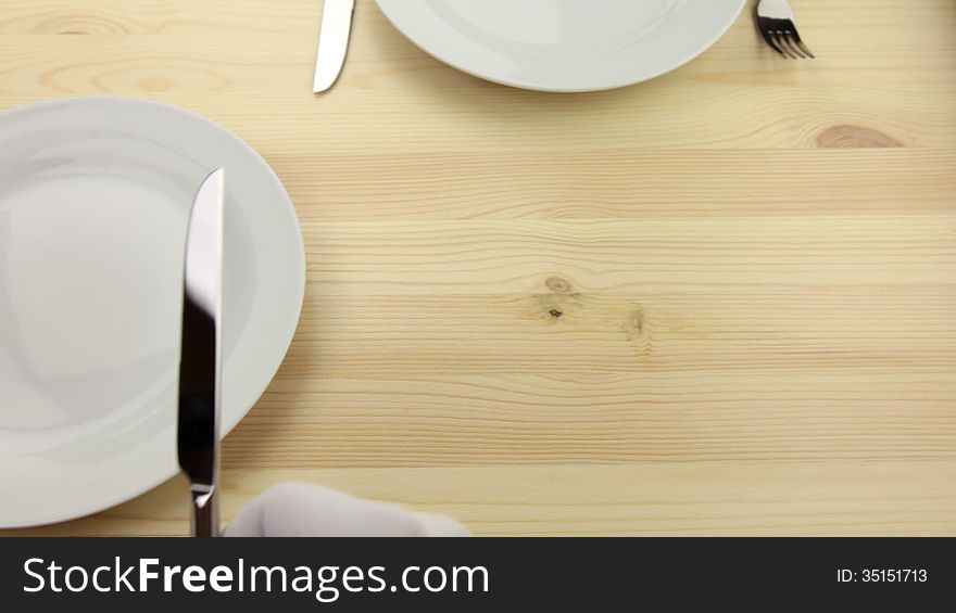 Wooden table. White plates. Hands waiters in white gloves, put a knife and fork. Wooden table. White plates. Hands waiters in white gloves, put a knife and fork