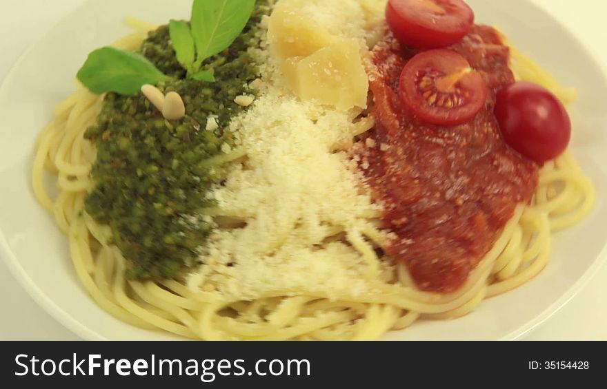 On a white plate rotates pasta. On top of pasta - Pesto, Parmesan and Tomato sauce - in the national colors of the Italian flag. On a white plate rotates pasta. On top of pasta - Pesto, Parmesan and Tomato sauce - in the national colors of the Italian flag