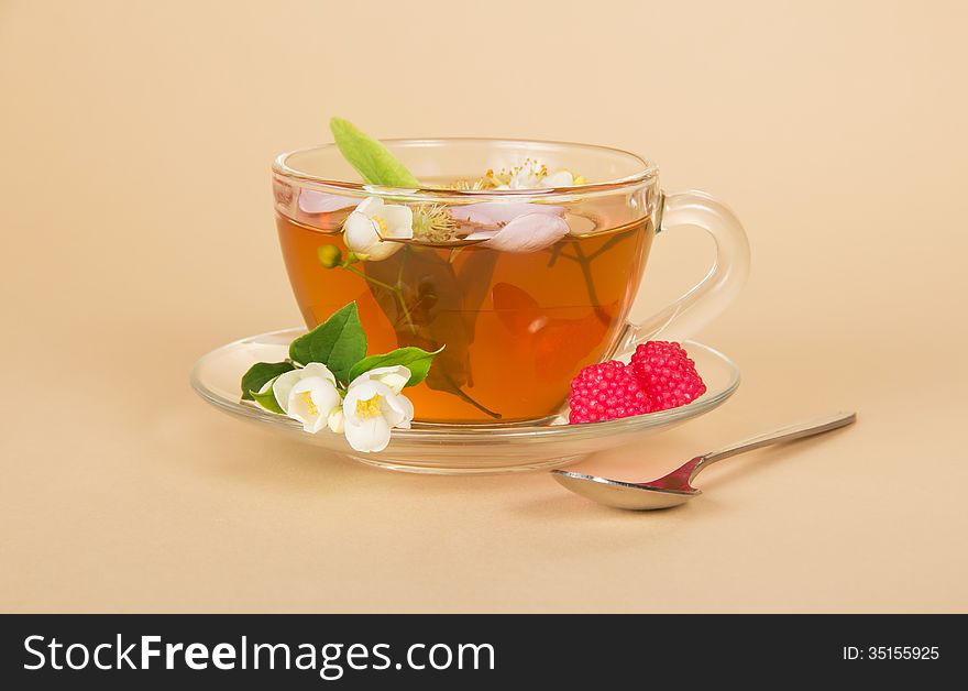 Cup of flower tea spoon and raspberry on beige