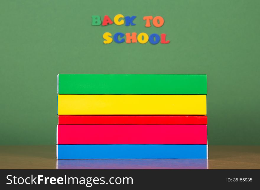 Stack of books and set of plastic letters, on a green background. Stack of books and set of plastic letters, on a green background