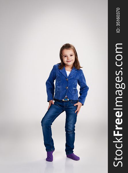 Little Girl In Blue Jeans And Jacket Posing In The Studio