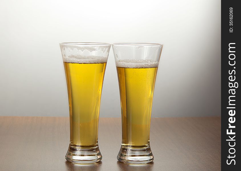 Two mugs of tasty fresh beer on a gray background