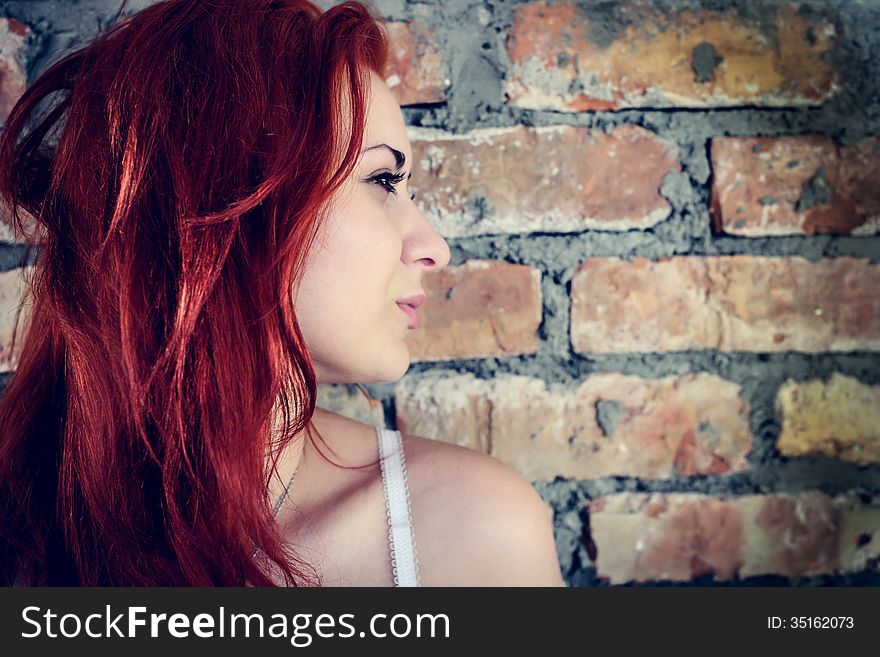 Portrait of red woman against brick wall outdoors