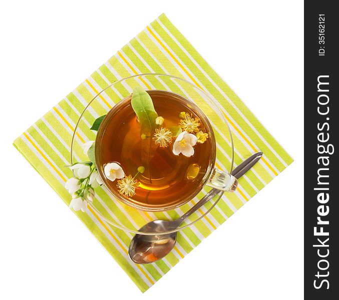 Flower tea in a cup with a saucer, a spoon, a napkin isolated on white. Flower tea in a cup with a saucer, a spoon, a napkin isolated on white
