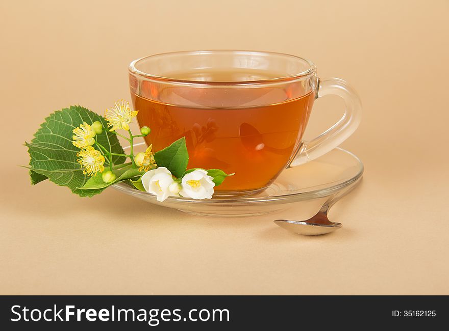 Cup of tea, linden and jasmine flowers, on a beige background