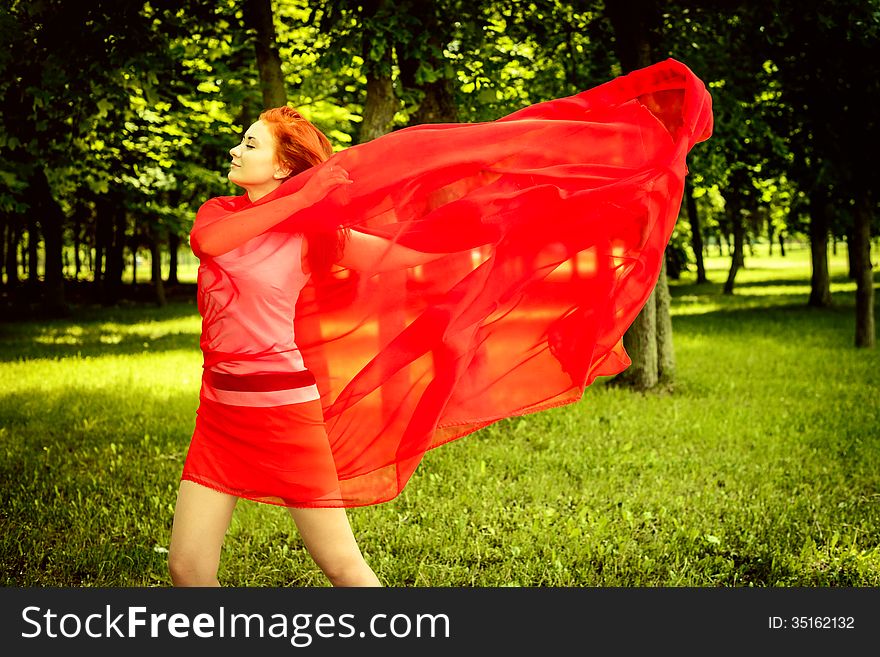 Happy woman in red rejoices to wind