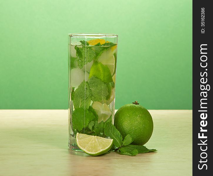 Glass of a mojito, spearmint leaf and juicy lime on a table