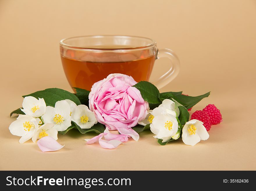 Cup of tea, branches of a jasmine and a rose on a beige background. Cup of tea, branches of a jasmine and a rose on a beige background