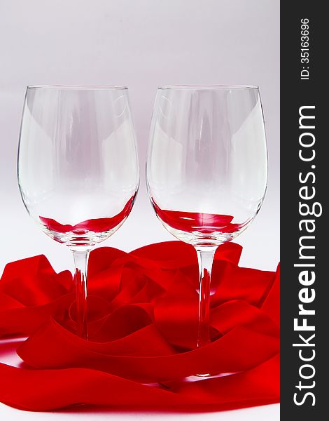 Empty wineglasses with red ribbon on white background