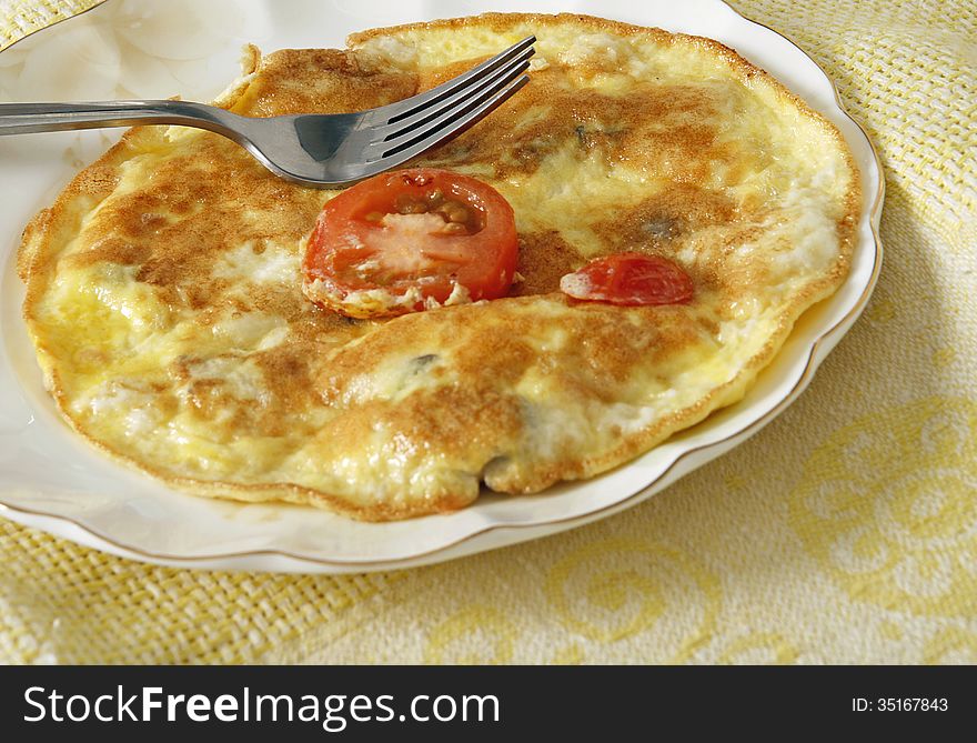 Fried egg omlet with tomato in a plate.