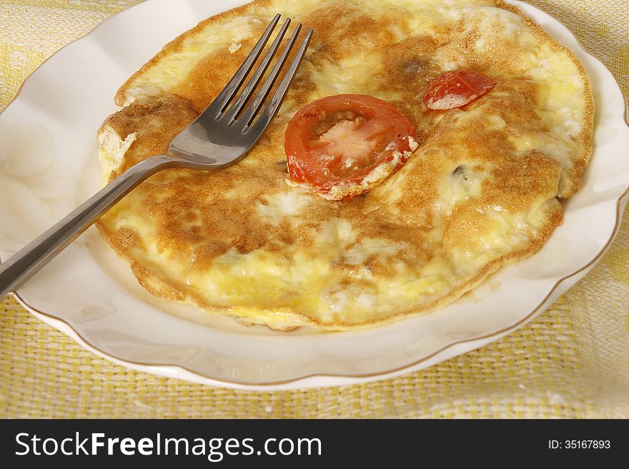 Fried egg omlet with tomato in a plate.