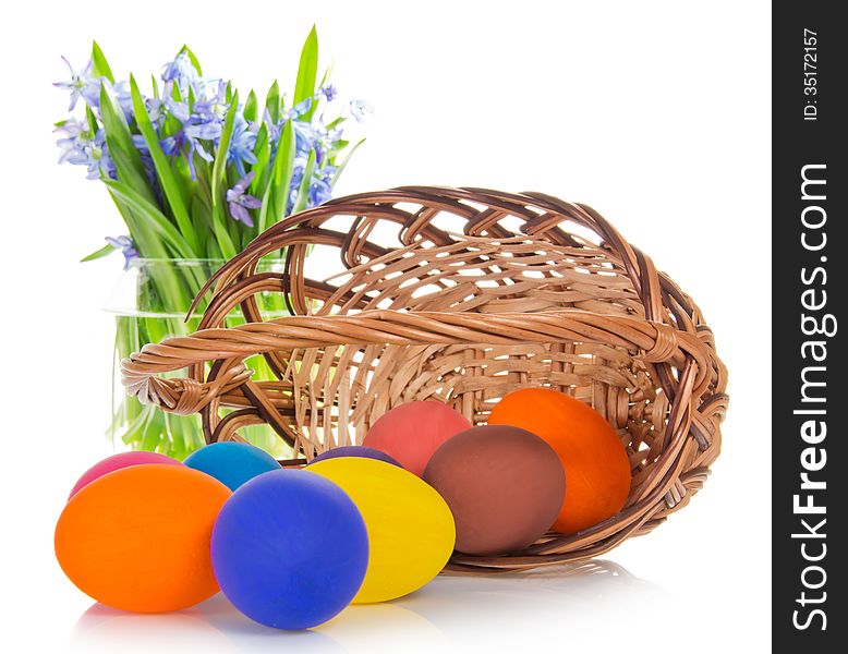 Bright eggs before a basket and flowers in a vase, isolated on white