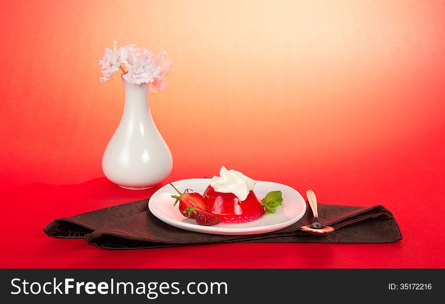 Plate with jelly and whipped cream, a spoon and a brown napkin on the pink