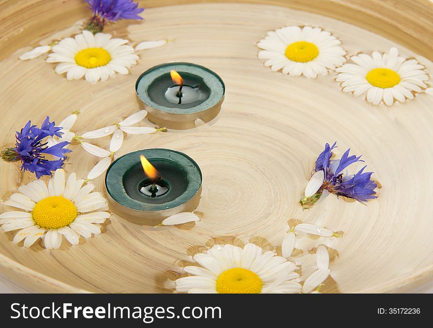 Camomiles, the cornflowers, burning candles in a platter with water