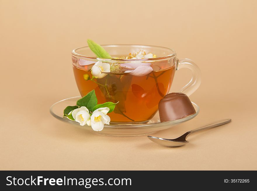 Cup of flower tea and the chocolate, on a beige background