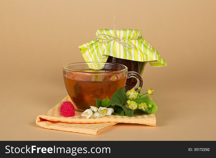 Raspberry jam, tea, flowers, napkin on a beige background
