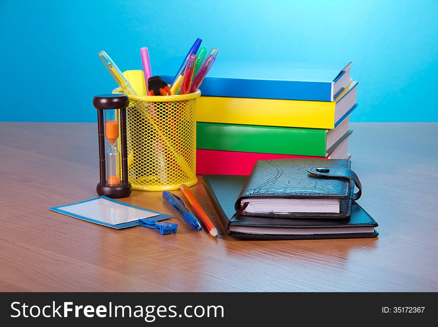 Organizer, notepad, books, blank badge, pens in a support, and hourglasses on a table. Organizer, notepad, books, blank badge, pens in a support, and hourglasses on a table