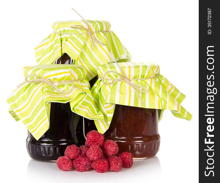 Jars of jam and a handful of the ripe raspberry, isolated on white