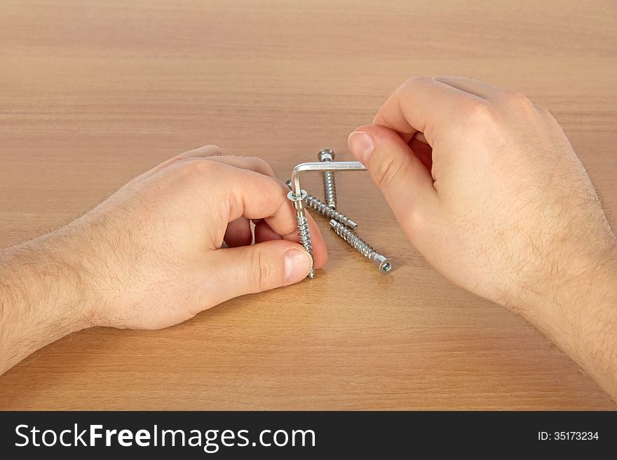 The hands working with the screw, on a beige background