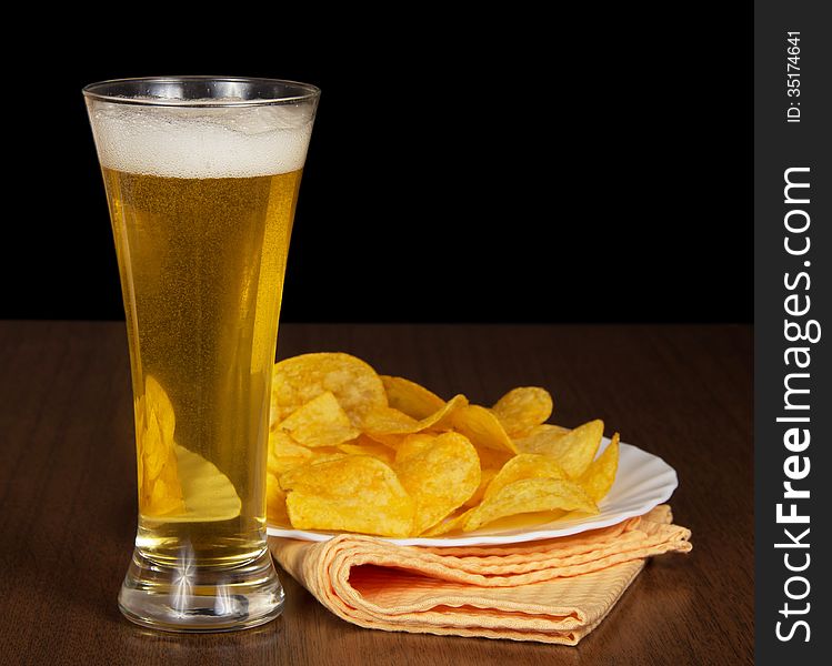 Mug with beer, a dish with chips and a napkin on a table. Mug with beer, a dish with chips and a napkin on a table