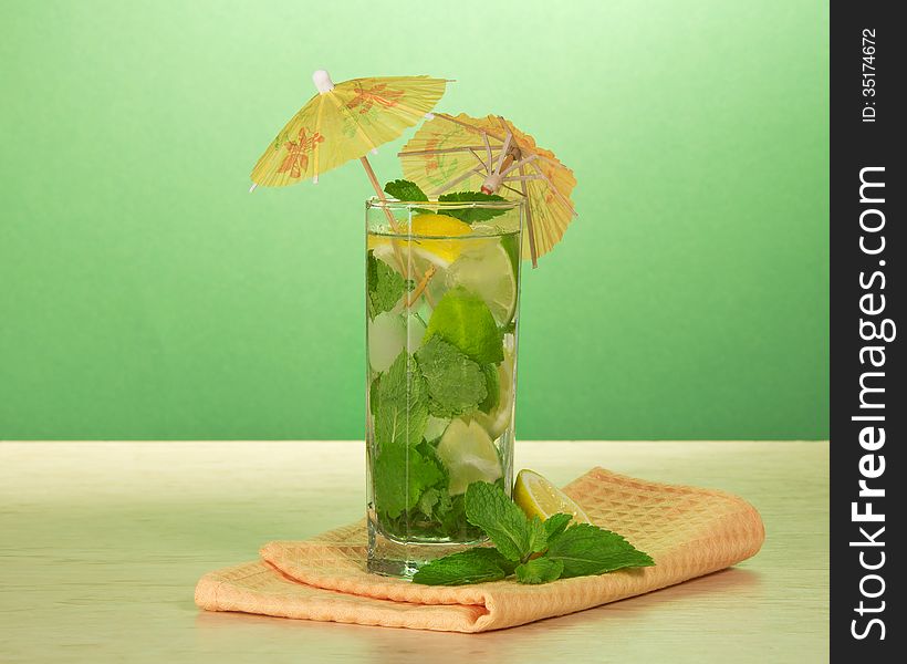 Cocktail from a citrus, ornament, spearmint and a napkin on a table