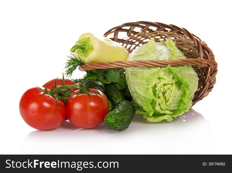The cabbage, cucumbers, tomatoes and greens, dropped out of a basket, isolated on white. The cabbage, cucumbers, tomatoes and greens, dropped out of a basket, isolated on white