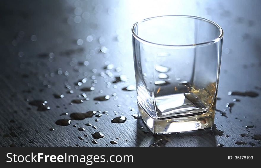 Pouring drinking water into glass on the table with splashed drop on the table