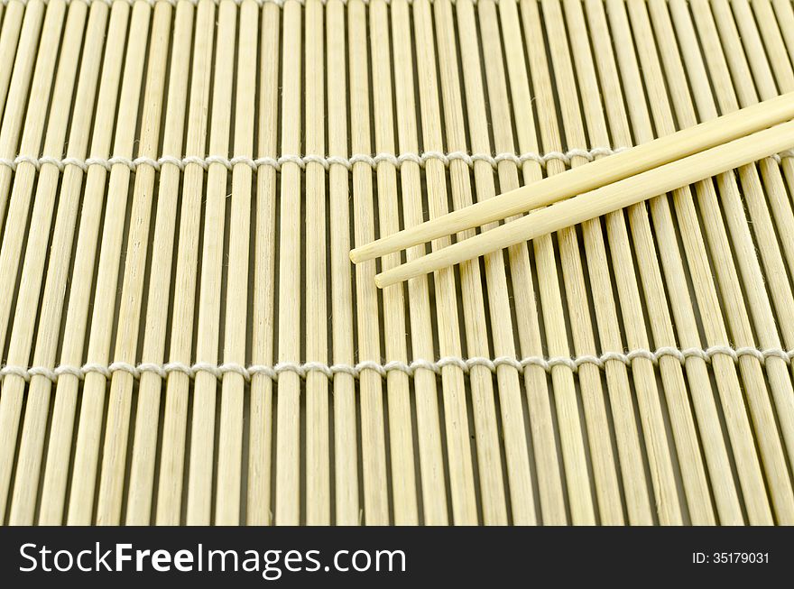 Two chopsticks on sushi mat background for menu