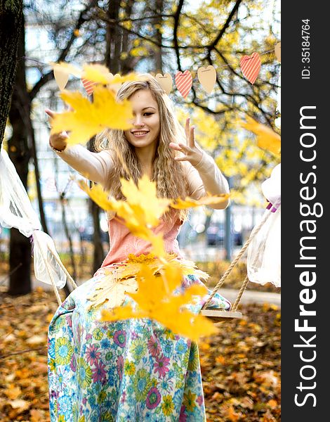 Happy girl throws colorful autumn leaves