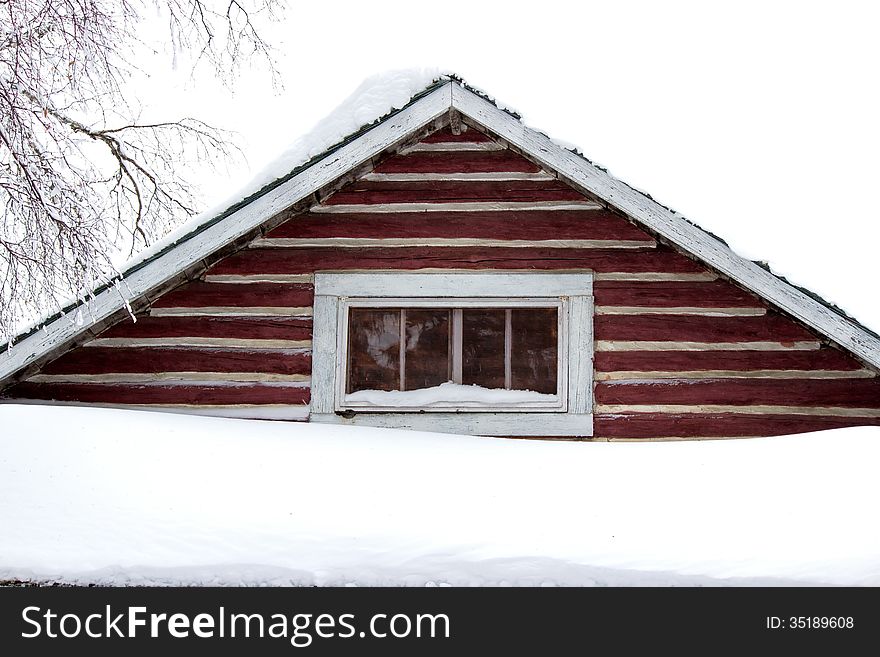 The peak of a red log cabin with snow on top. The peak of a red log cabin with snow on top