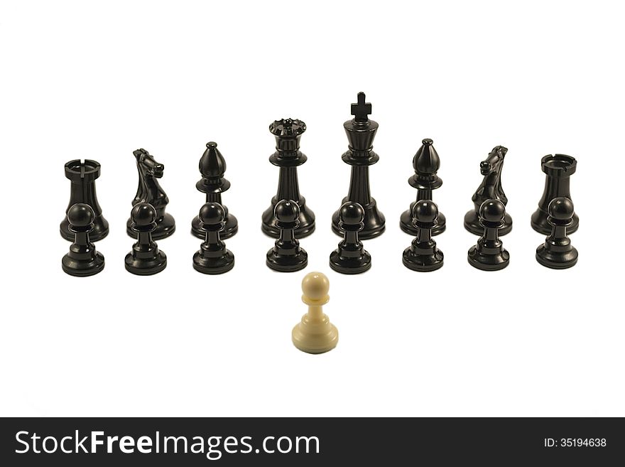 White pawn standing in front of the aligned black chess pieces. White pawn standing in front of the aligned black chess pieces.