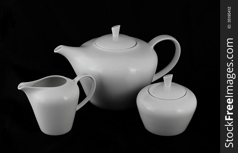 Set of white porcelain jugs and sugar bowl on a black background. Set of white porcelain jugs and sugar bowl on a black background