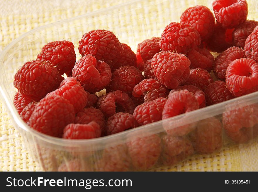Ripe raspberry in a plastic container.