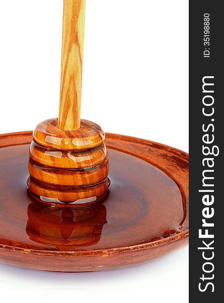 Wooden Dipper with Honey Standing into Brown Plate isolated on white background. Wooden Dipper with Honey Standing into Brown Plate isolated on white background