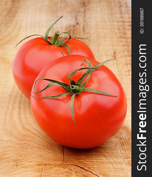 Two Perfect Ripe Tomatoes with Twigs closeup on Wooden background. Two Perfect Ripe Tomatoes with Twigs closeup on Wooden background