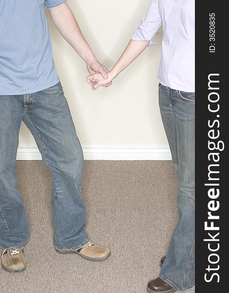 Close up front view of heterosexual couple standing holding hands wearing casual clothing. Close up front view of heterosexual couple standing holding hands wearing casual clothing