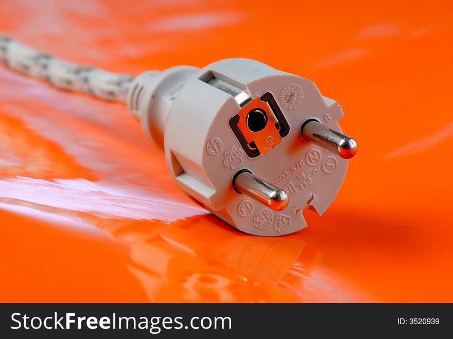 Electric plug on  bright, orange background, close up